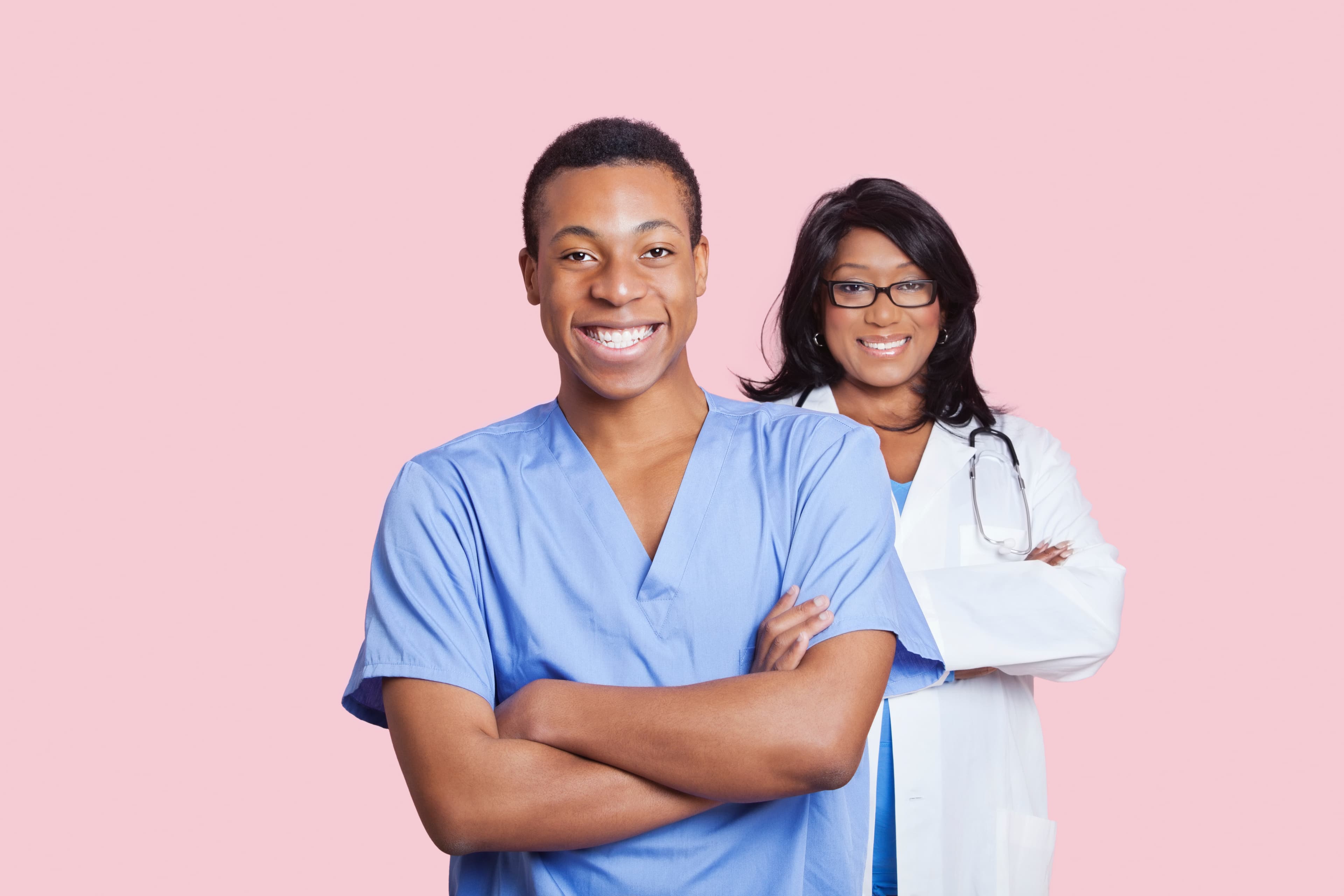 Portrait of confident mixed race male and female healthcare workers over pink background